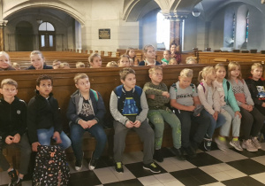 Uczniowie klas trzecich w ławkach nawy głównej kościoła